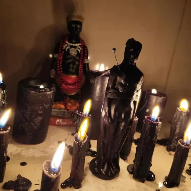 Figura negra entre velas negras encendidas