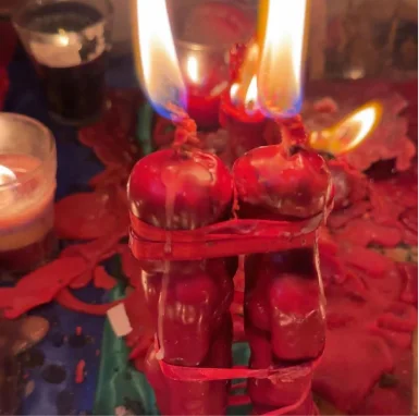 Dos velas rojas unidas con cinta roja, encendidas